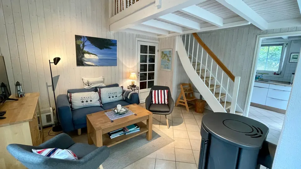 Wohnraum mit blauem Sofa, Kaminofen und Treppe zur Galerie